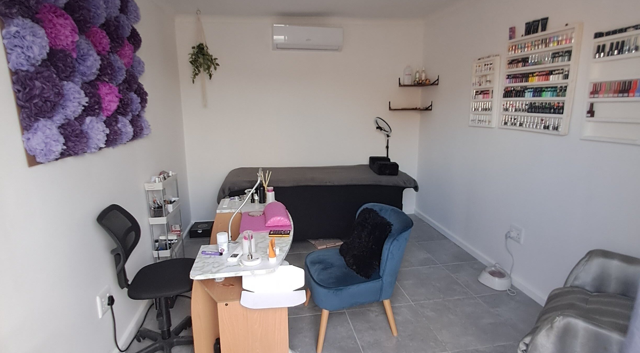 Cozy treatment room at All Things Beautiful, Cape Town, Western Cape, ZA, with plush seating and nail polish display.