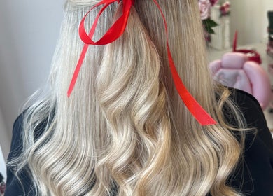 Long, wavy blonde hair styled with a red ribbon at Hair by Harriet in Nuneaton, England, GB.