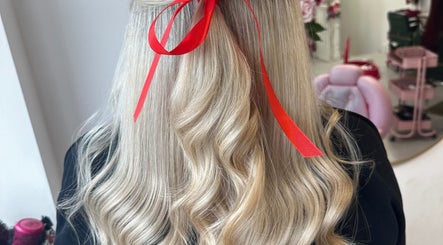 Long, wavy blonde hair styled with a red ribbon at Hair by Harriet in Nuneaton, England, GB.