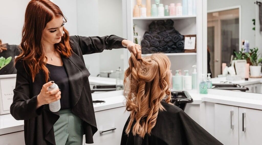Stylist at Mel Watson Hairstylist in Burlington, Ontario, CA perfecting elegant curls in client’s hair.