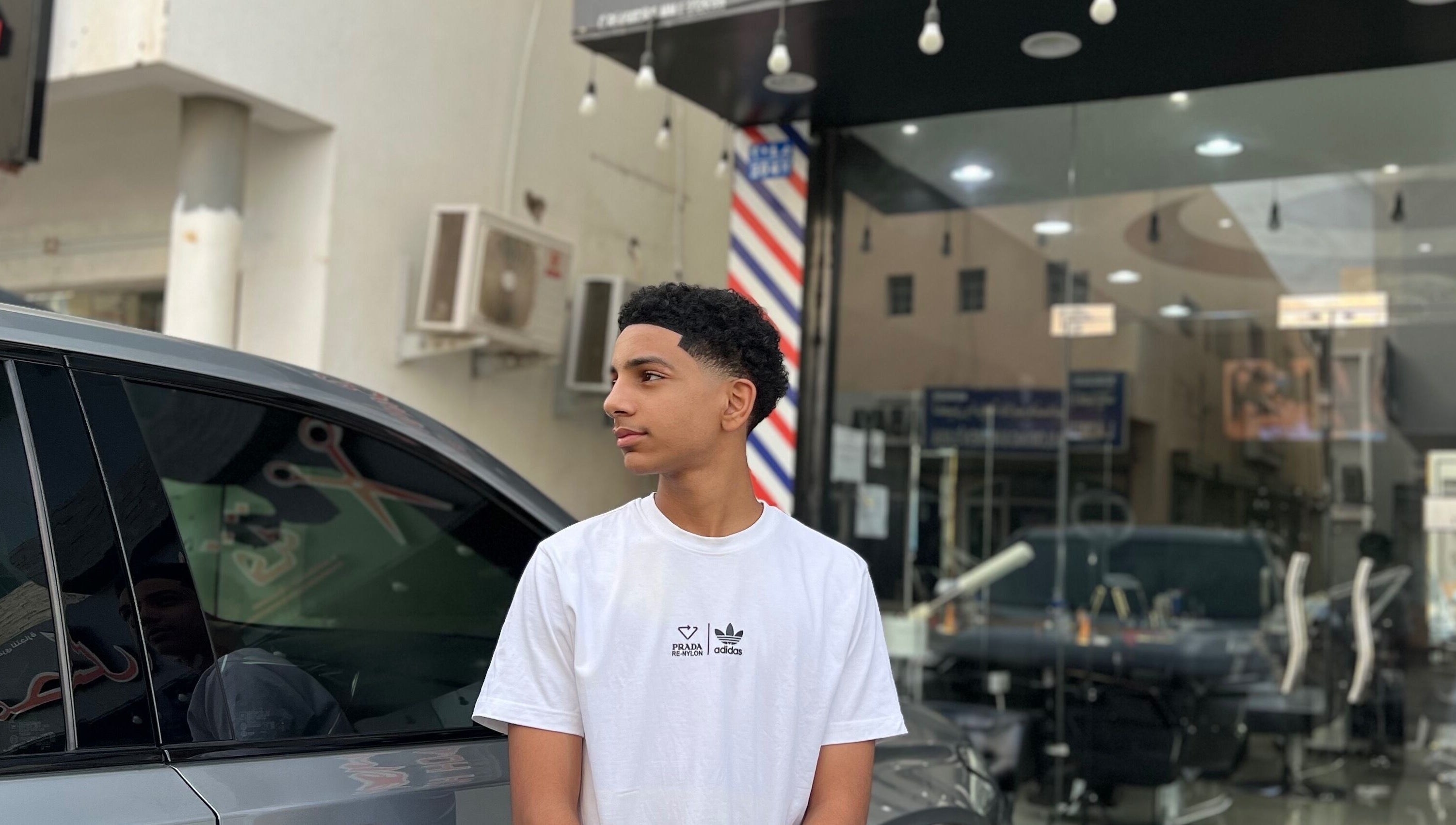 Young man outside Georgekutz Hair Studio, Seeb, Muscat Governorate, OM, showcasing a fresh haircut.