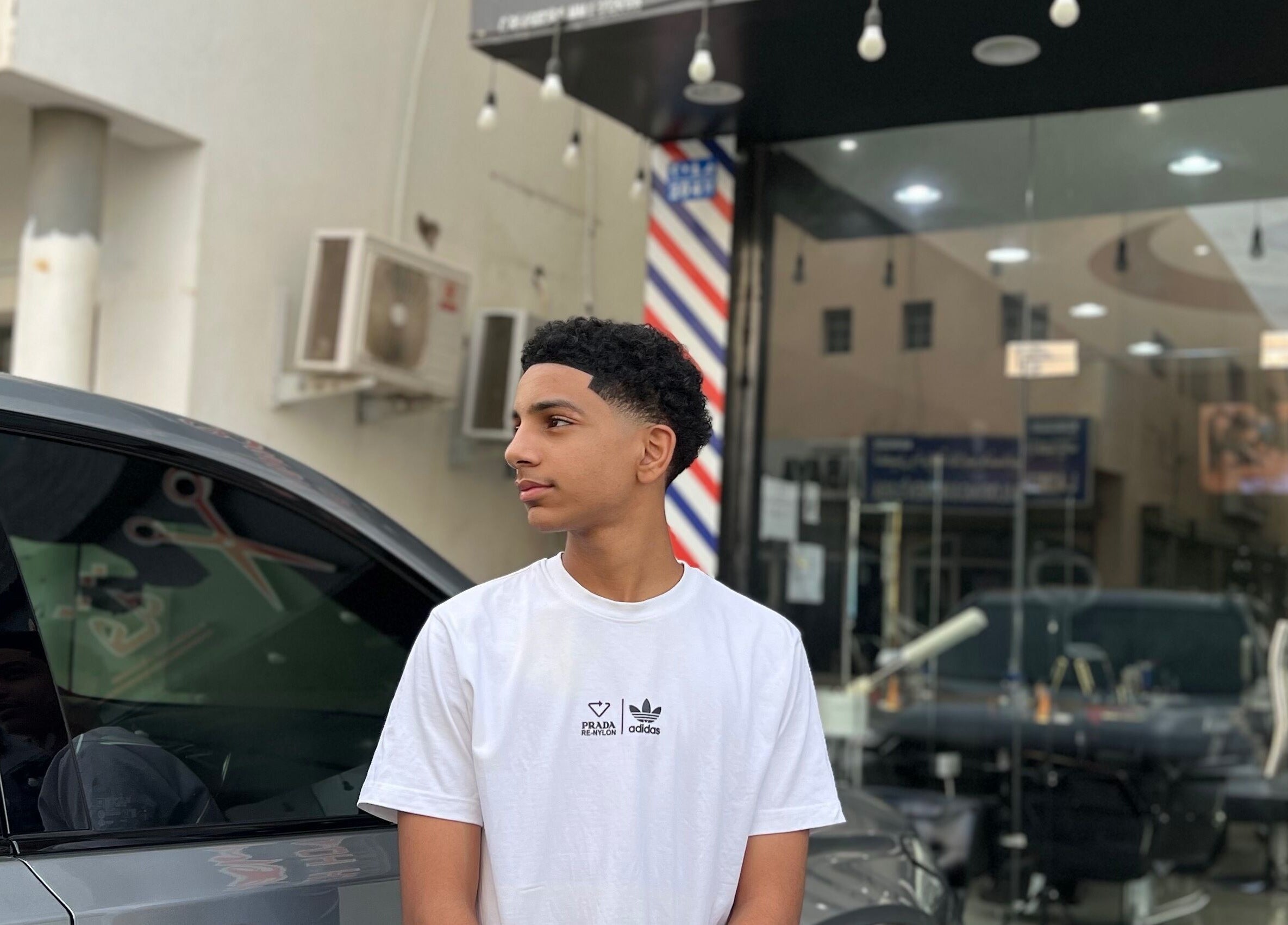 Young man outside Georgekutz Hair Studio, Seeb, Muscat Governorate, OM, showcasing a fresh haircut.