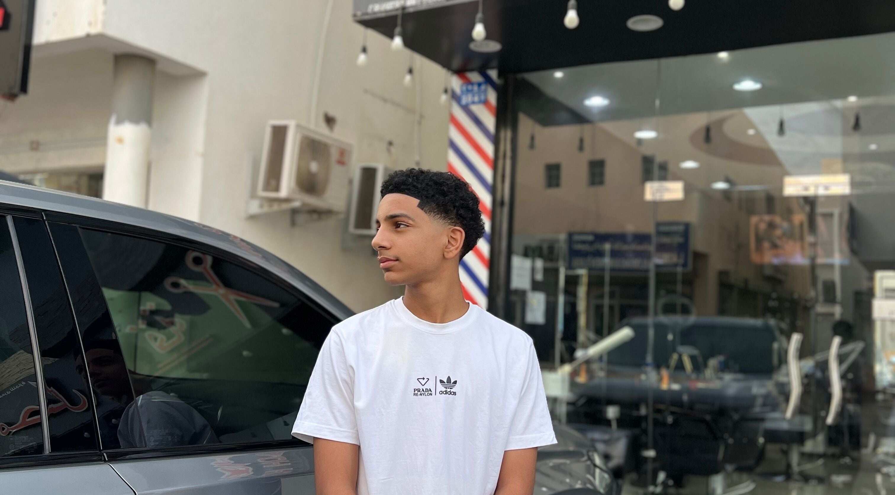 Young man outside Georgekutz Hair Studio, Seeb, Muscat Governorate, OM, showcasing a fresh haircut.