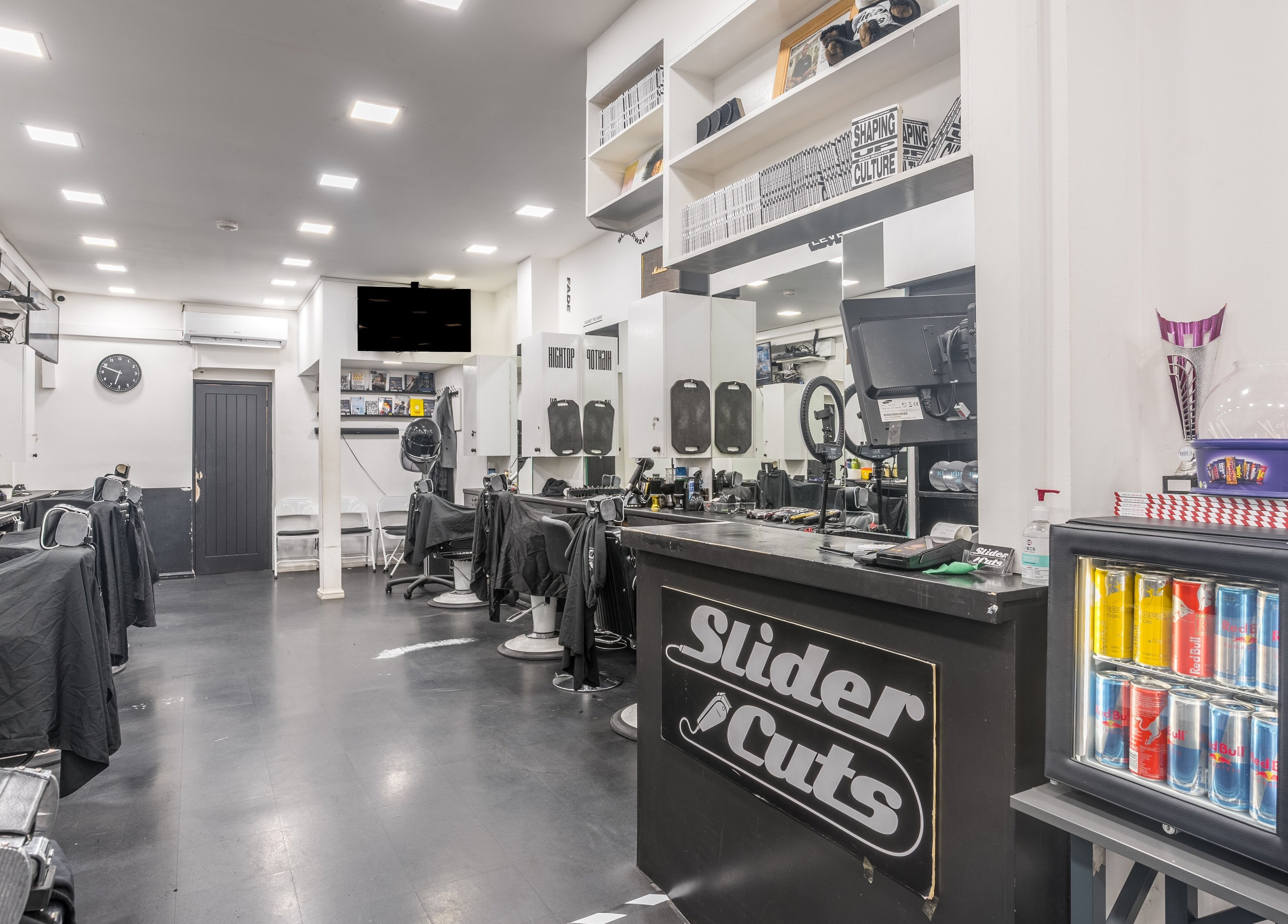 Inside SliderCuts, a sleek barber shop in London, England, GB showcasing chairs and styling stations.