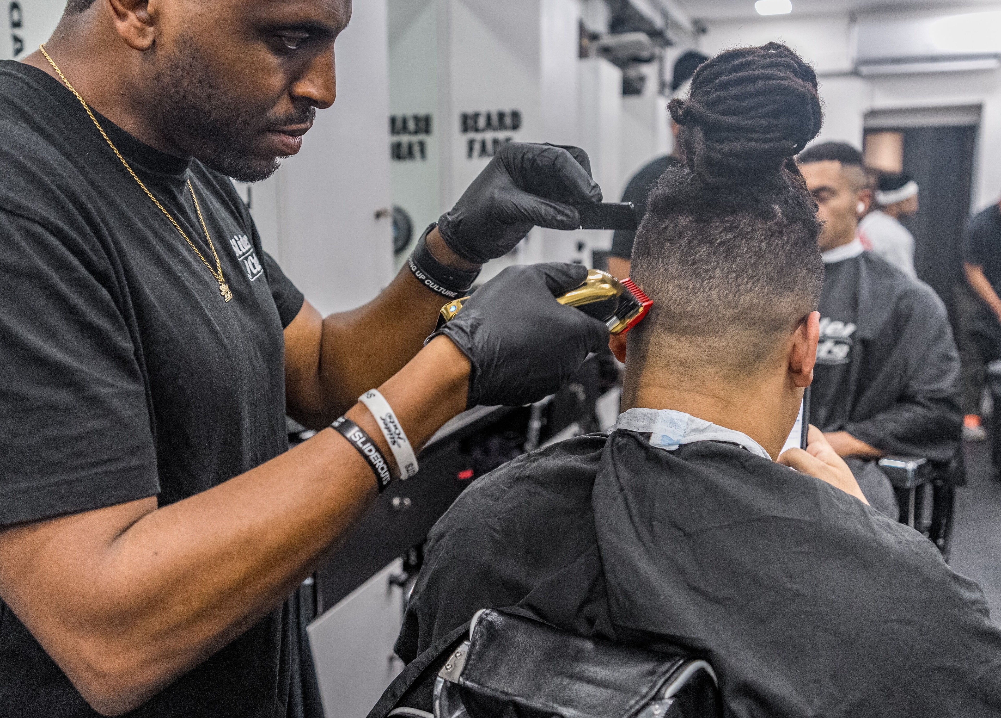 Barber at SliderCuts in London, England, GB, expertly cuts a client's hair in a modern salon setting.