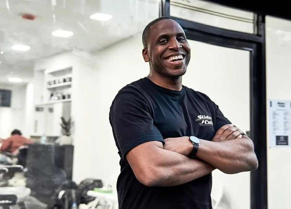 Stylist smiling at SliderCuts, London, England, GB, showcasing the welcoming vibe of this hair salon.