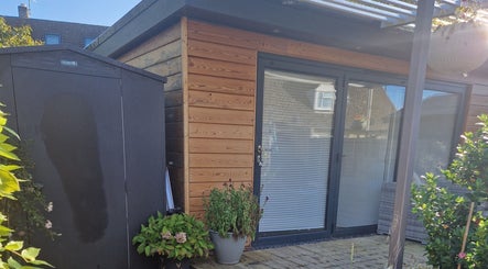 Charming garden view at Aura10 in Long Hanborough, GB, featuring a wooden cabin and lush greenery.