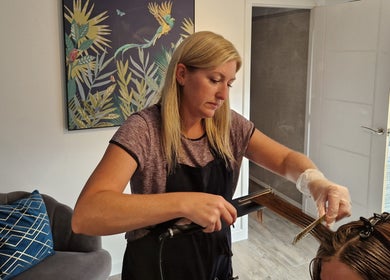 Stylist at Aura10, Long Hanborough, GB, expertly straightening hair in a serene salon setting.