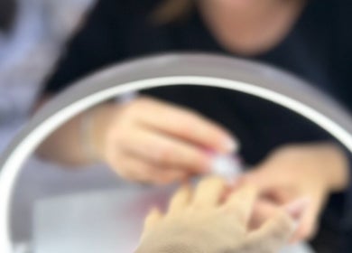 Nail artist at JenLee Beauty in Pretoria, Gauteng, ZA, skillfully polishing nails under perfect lighting.