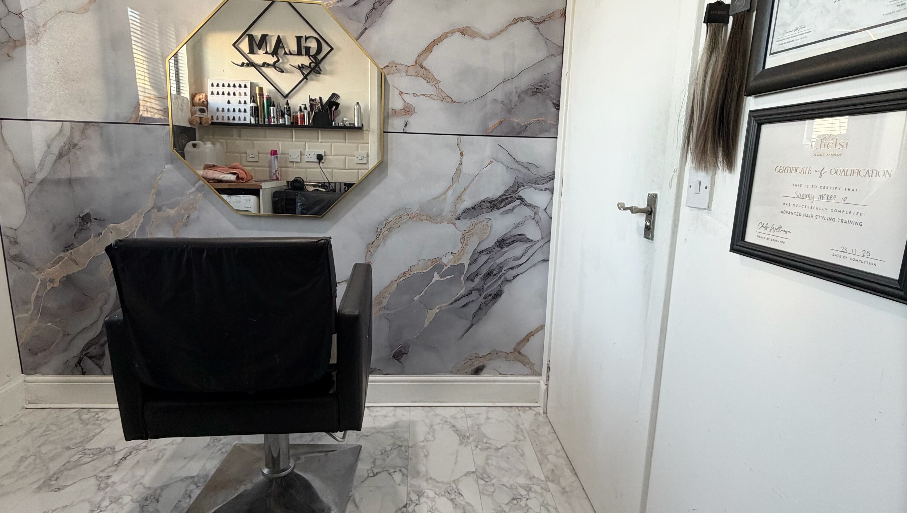 Interior view of Glambysam salon in Glasgow, Scotland, featuring a stylish chair and elegant wall decor.