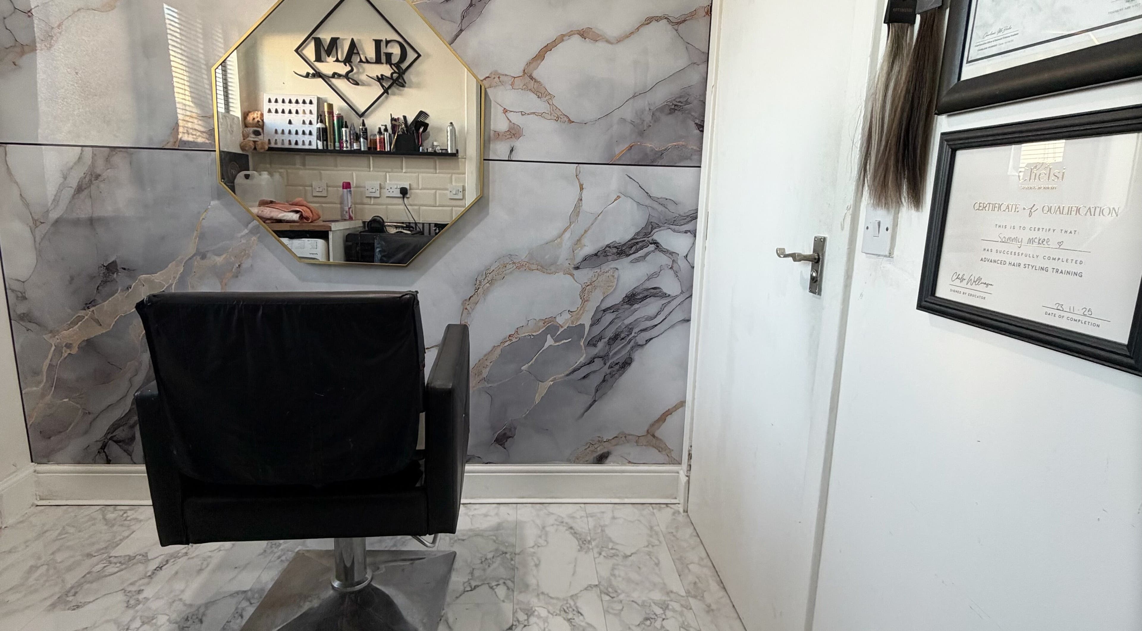 Interior view of Glambysam salon in Glasgow, Scotland, featuring a stylish chair and elegant wall decor.