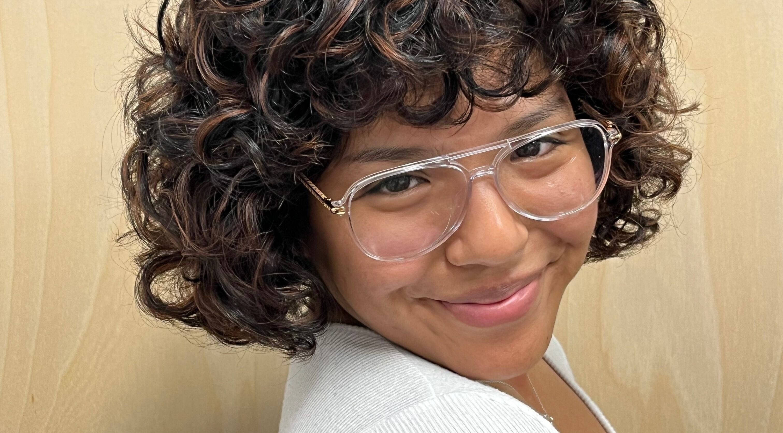 Smiling woman with curly hair and glasses at Tailored Hair Studio - Phoenix, Phoenix, Arizona, US.