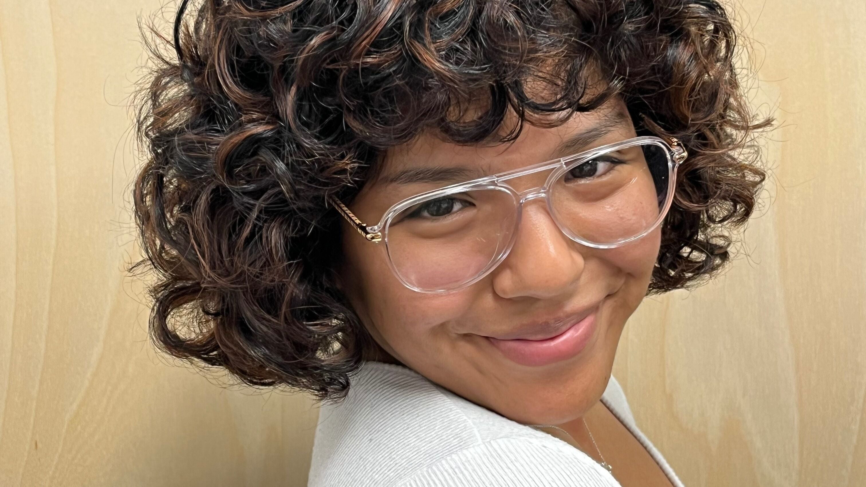 Smiling woman with curly hair and glasses at Tailored Hair Studio - Phoenix, Phoenix, Arizona, US.