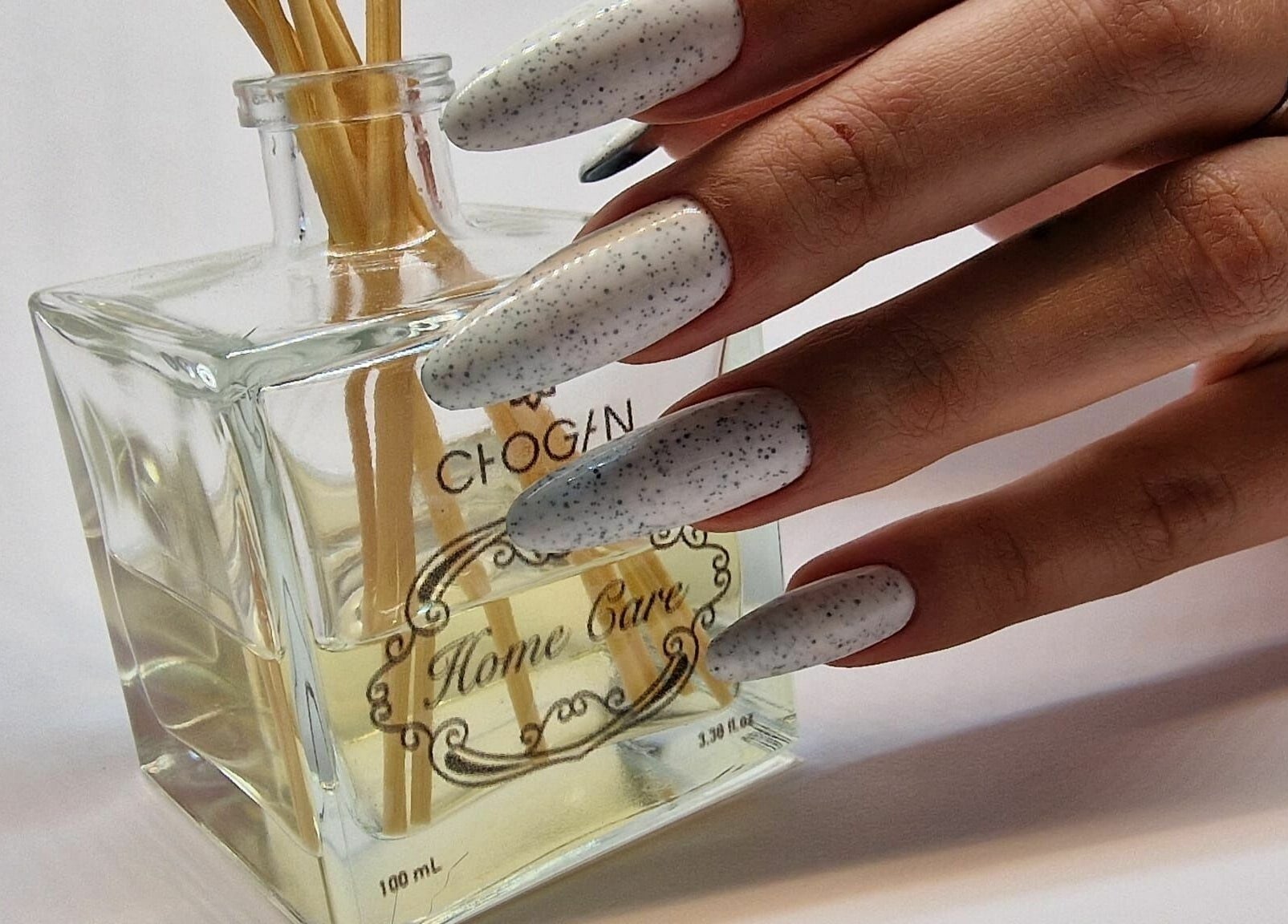 Unghie eleganti con design a pois presso Ala Nails Studio, Lugano, Ticino, CH, accanto a profumo elegante.