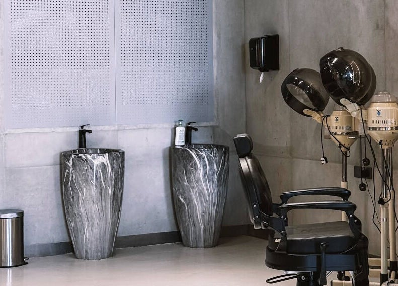 Modern interior of 9CUTS Barber Shop in Riyadh, featuring stylish marble sinks and vintage hair dryers.