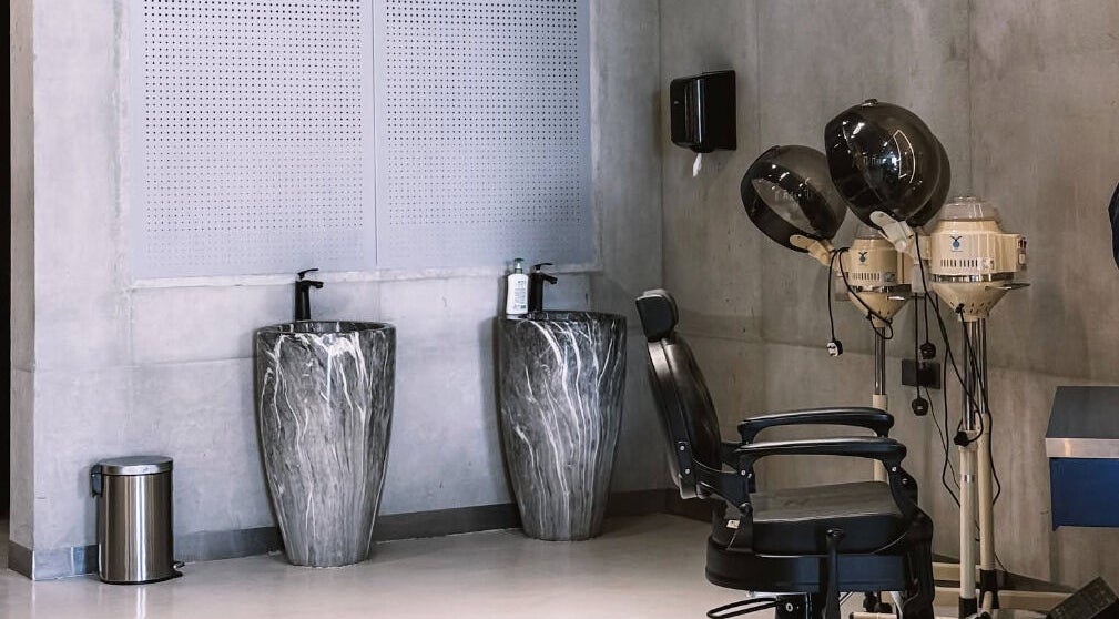 Modern interior of 9CUTS Barber Shop in Riyadh, featuring stylish marble sinks and vintage hair dryers.