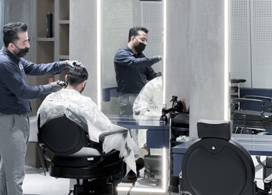 Barber at 9CUTS Barber Shop in Riyadh I الرياض, SA, expertly styles a client's hair.