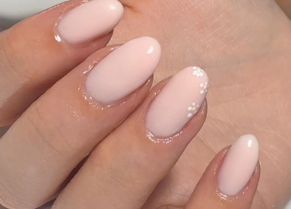 Soft pink manicured nails with white floral design at Bymolh, Lichfield, England, GB.