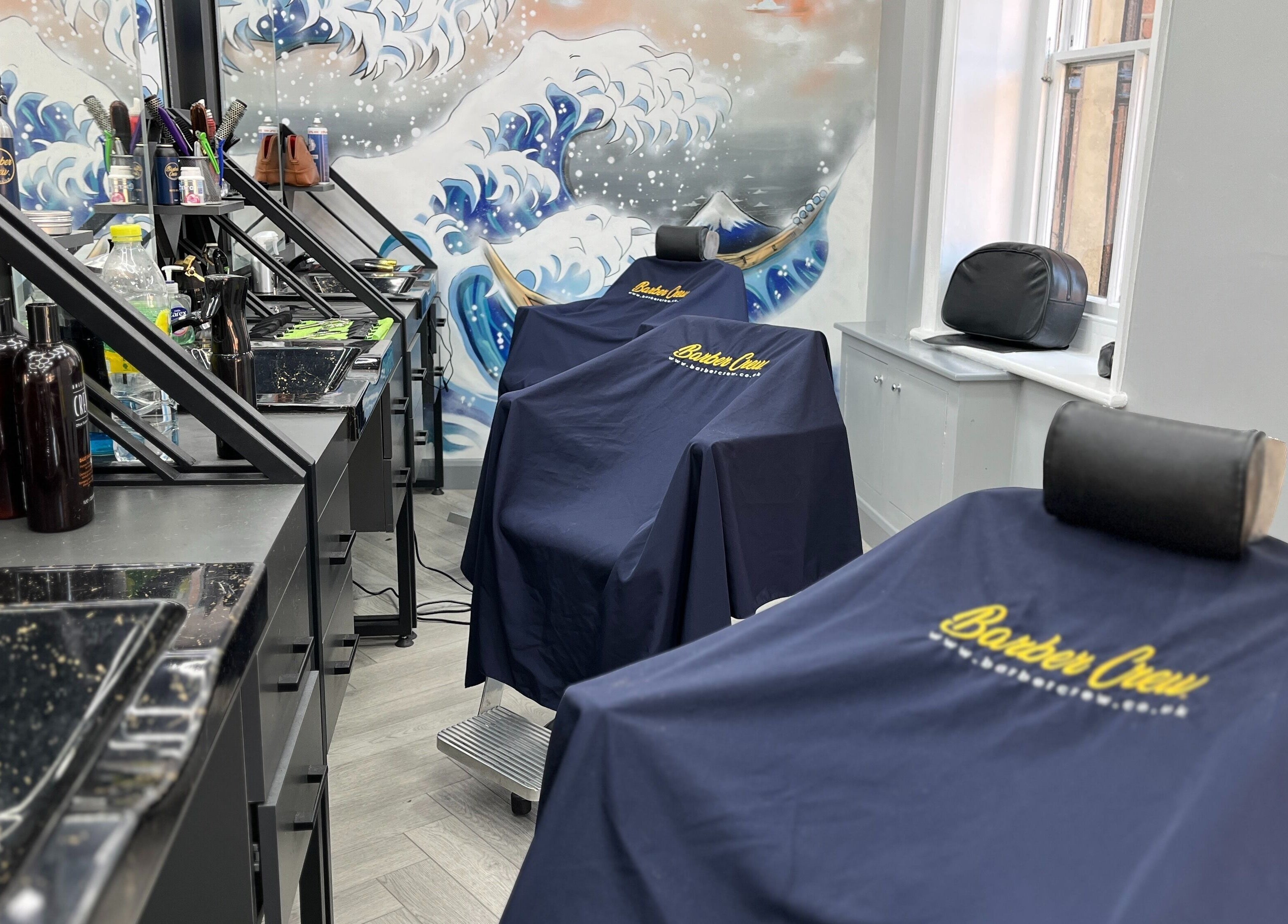 Barber chairs with branded covers at Barber Crew Wokingham, Wokingham, England, GB, showcasing professional setup.