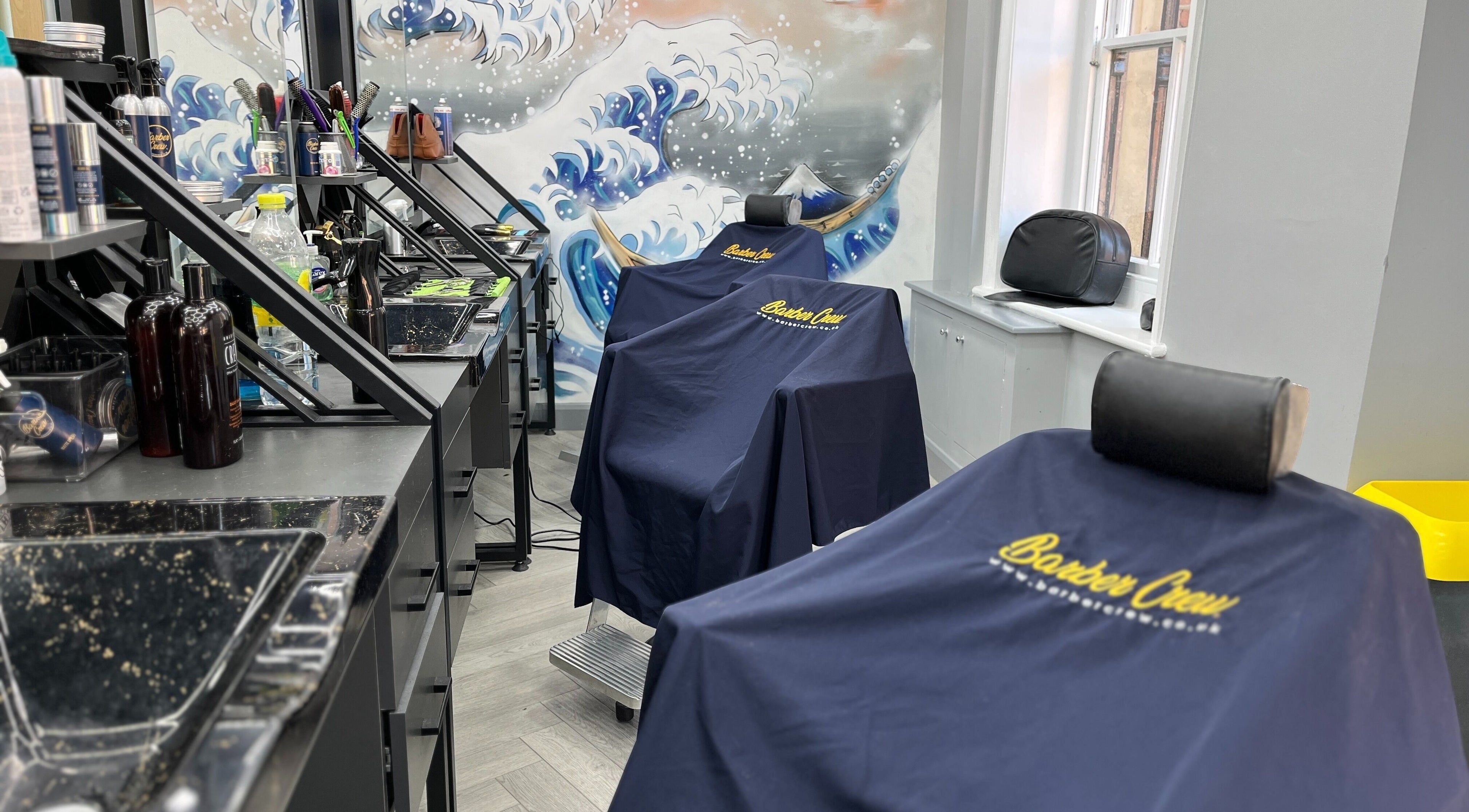 Barber chairs with branded covers at Barber Crew Wokingham, Wokingham, England, GB, showcasing professional setup.