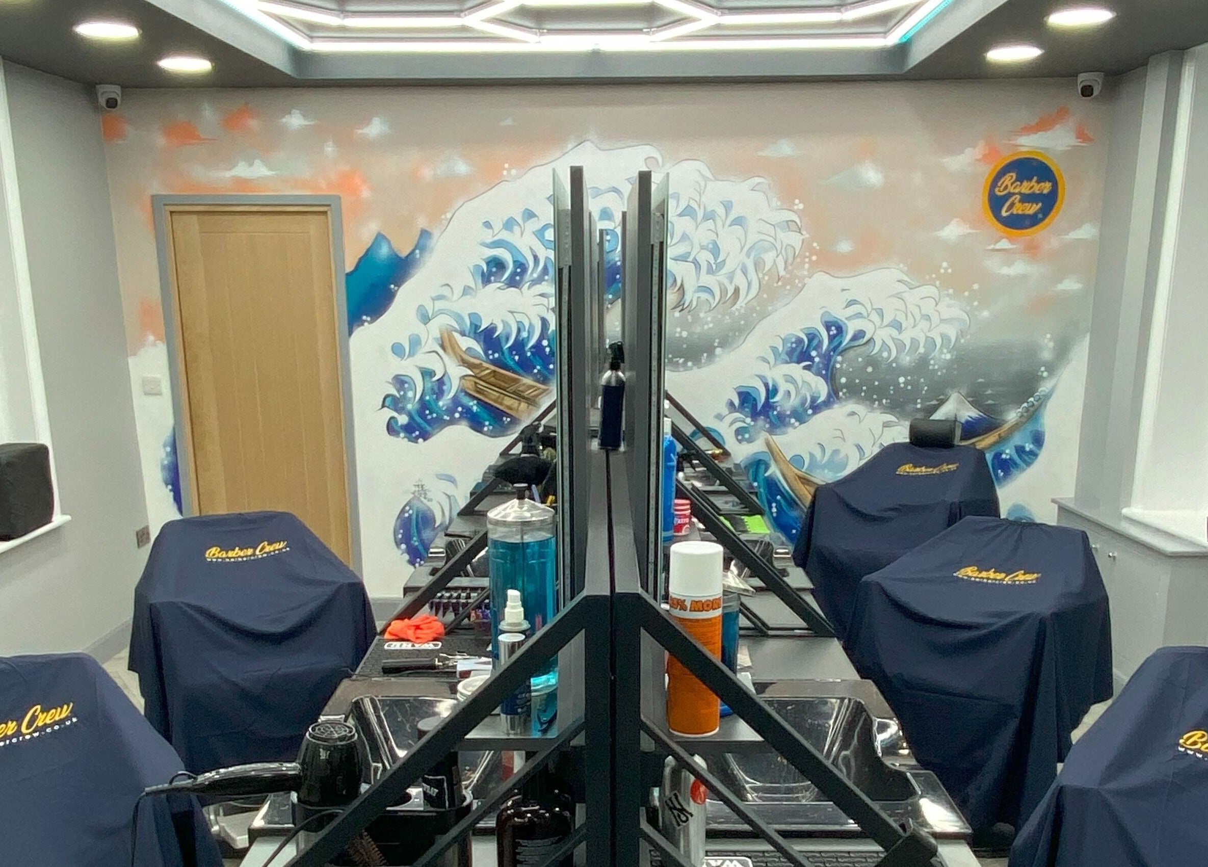 Modern interior of Barber Crew Wokingham in Wokingham, England with artistic wall design and salon stations.