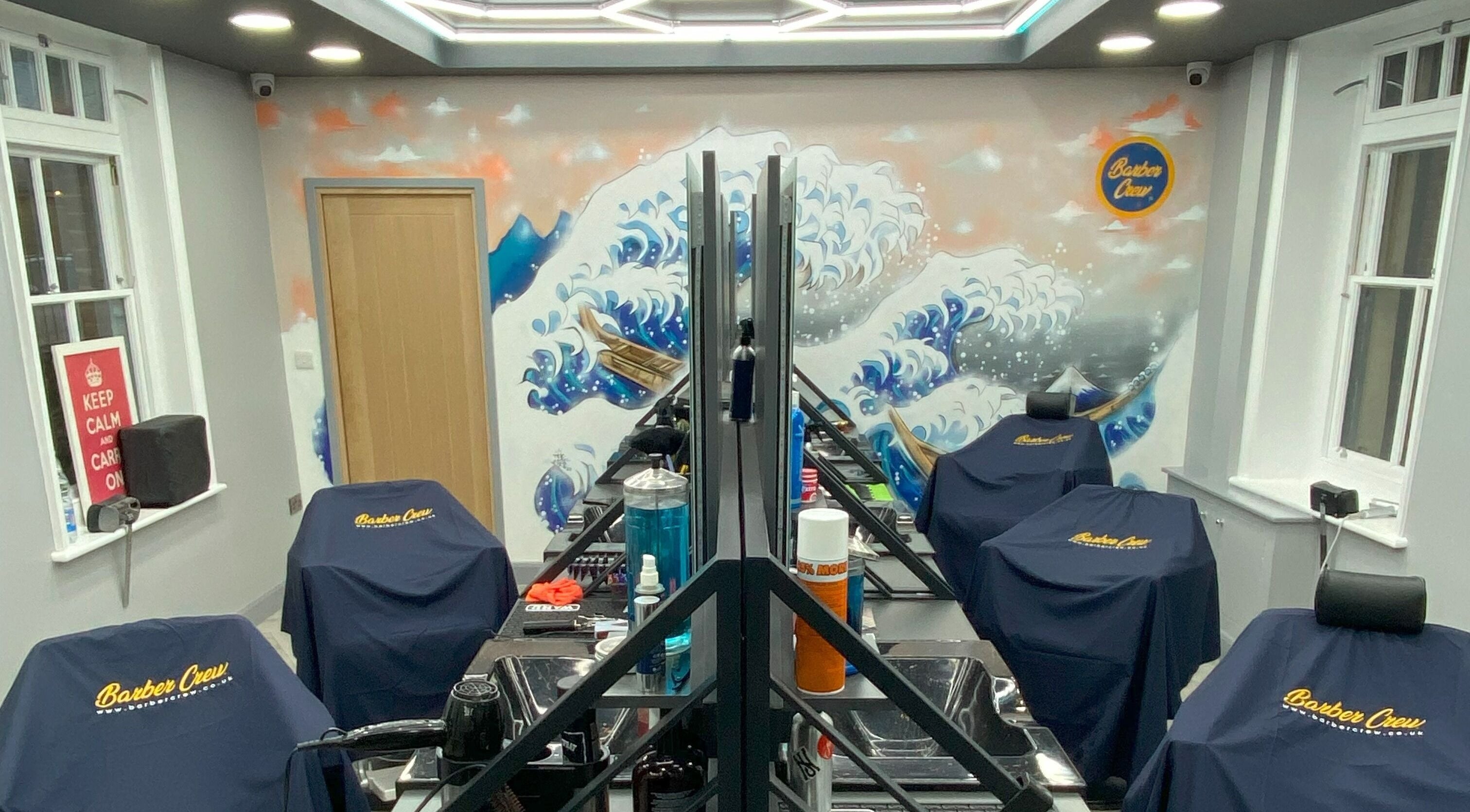 Modern interior of Barber Crew Wokingham in Wokingham, England with artistic wall design and salon stations.