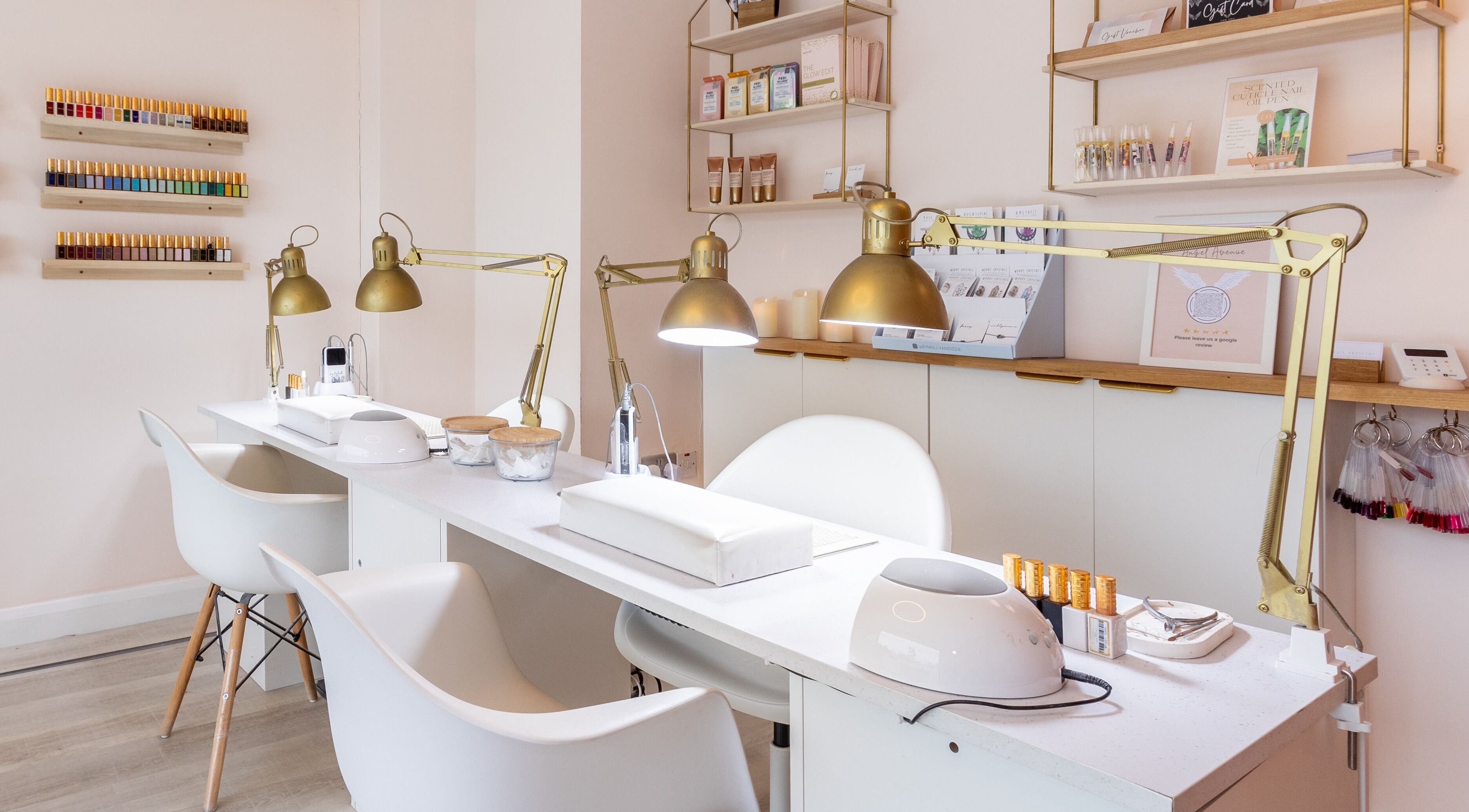 Chic nail salon setup at Angel Avenue, Atherton, England, GB, featuring modern white chairs and golden lamps.