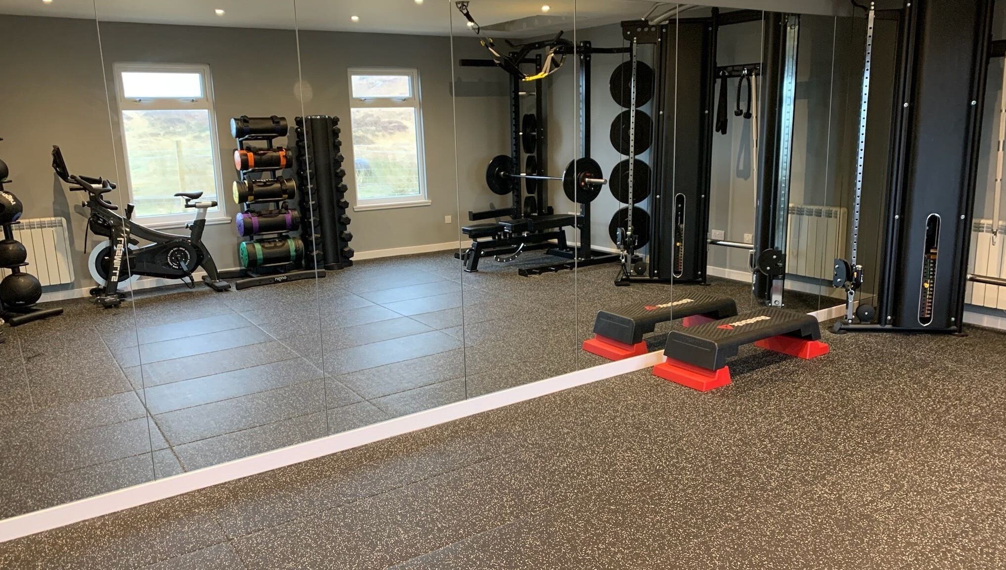 Modern gym at KB Fitness, Scotland, GB with equipment including bikes, weights, and a mirrored wall.