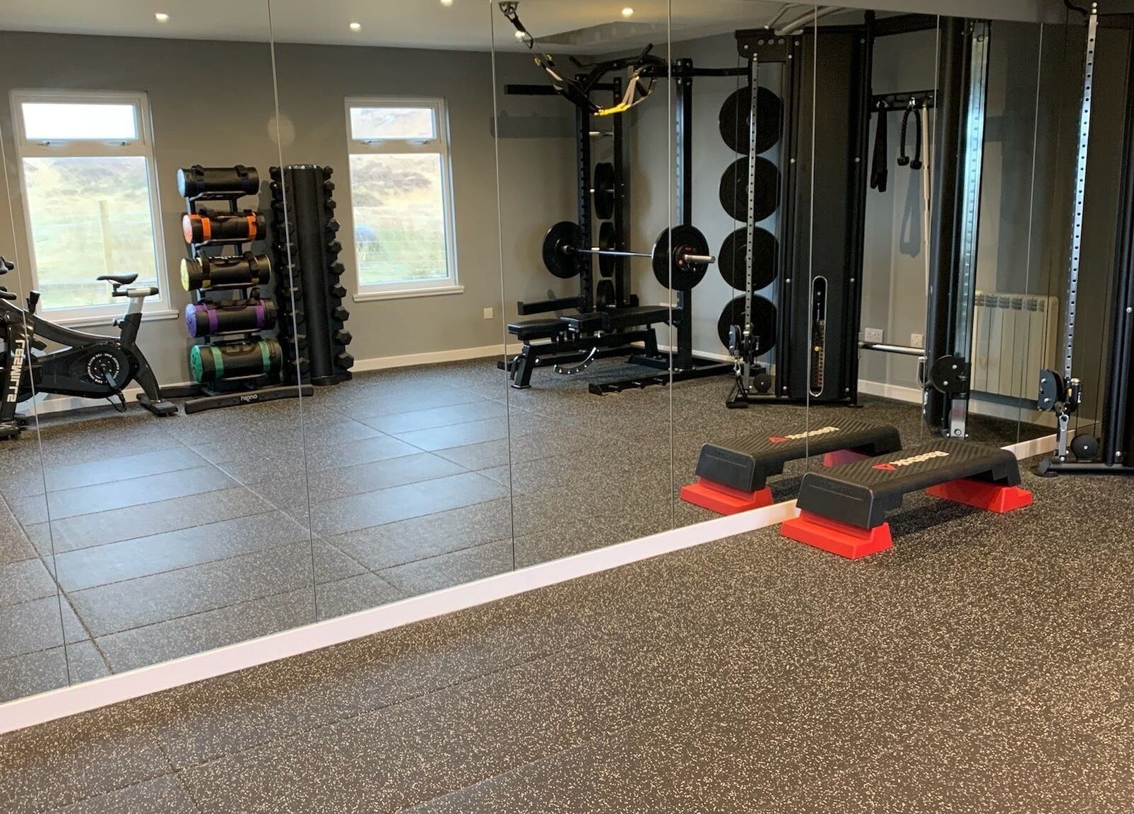 Modern gym at KB Fitness, Scotland, GB with equipment including bikes, weights, and a mirrored wall.