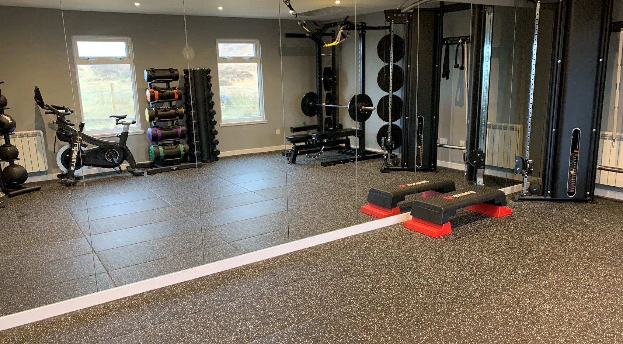 Modern gym at KB Fitness, Scotland, GB with equipment including bikes, weights, and a mirrored wall.