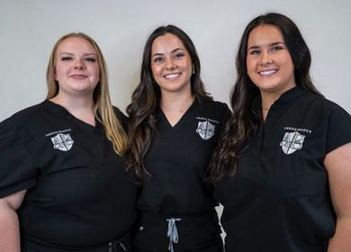 Three smiling team members at Armor Beauty, Knoxville, Tennessee, US, in branded attire.