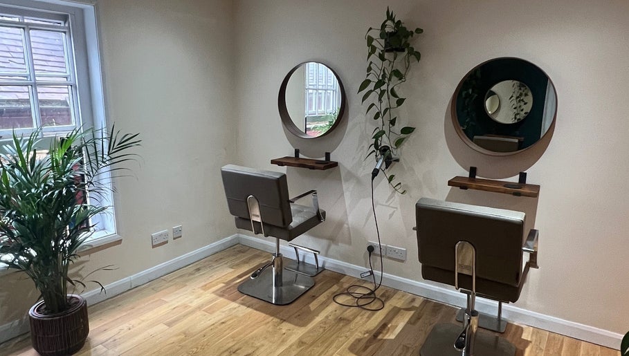 Cozy styling area at Natural Hair Studio, Horsham, England, GB with modern chairs and green plants.