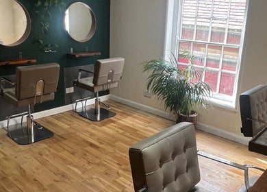 Elegant salon interior of Natural Hair Studio in Horsham, England, GB, featuring stylish chairs and mirrors.