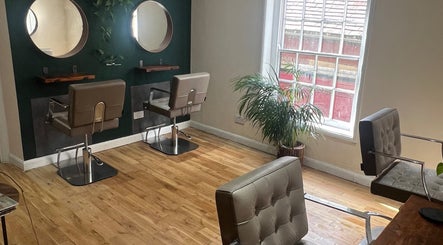 Elegant salon interior of Natural Hair Studio in Horsham, England, GB, featuring stylish chairs and mirrors.