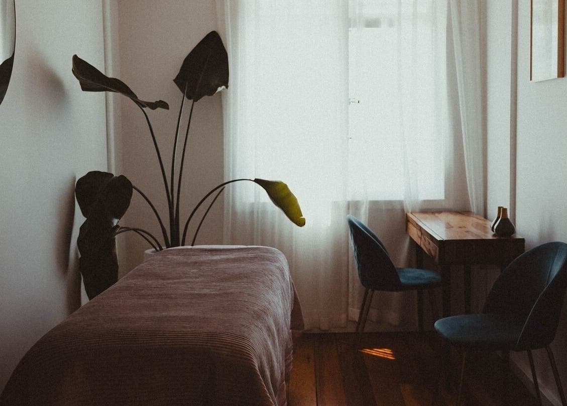 Tranquil treatment room at WYLD Howick, Auckland, NZ with cozy bed and greenery.