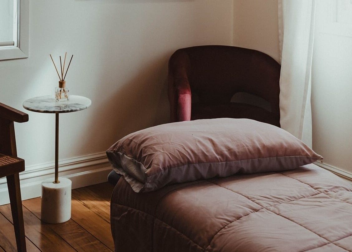 Cozy massage room at WYLD Howick, Auckland, NZ with plush bedding and elegant decor.