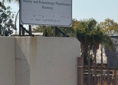 Ozone entrance sign in Roodepoort, Gauteng, ZA, framed by trees and a clear sky.