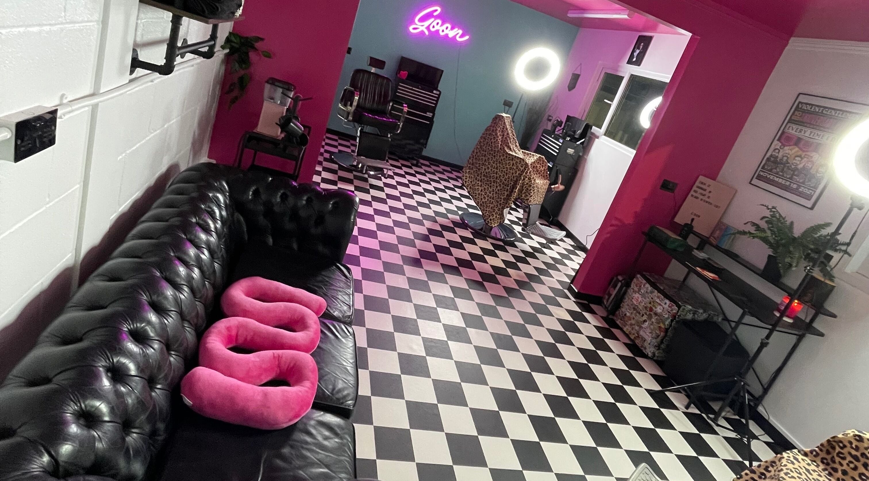 Chic interior of Goon Barbers, Dowlais, Wales featuring black sofas and unique décor with checkered flooring.