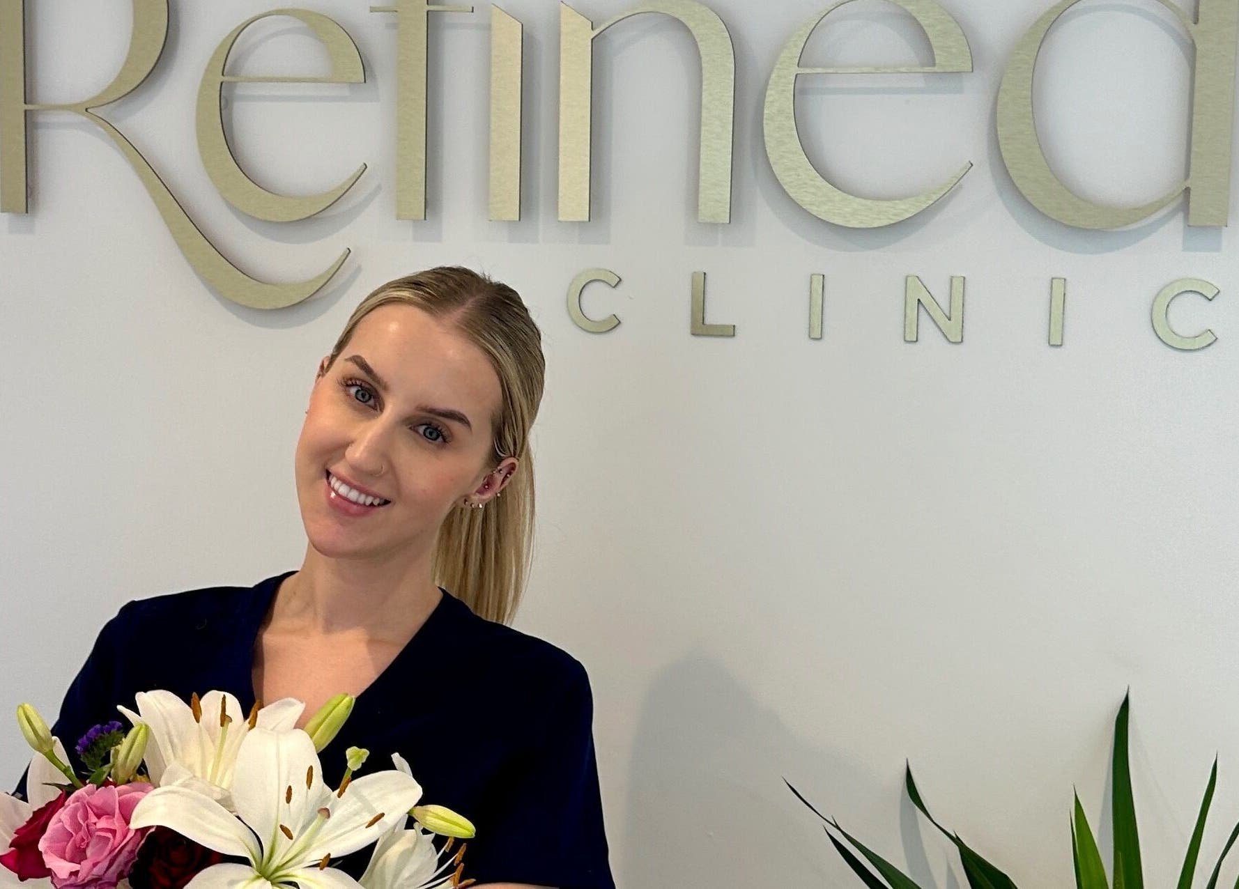 Staff member with flowers at Refined Clinic, Baildon, England, GB, smiling warmly.