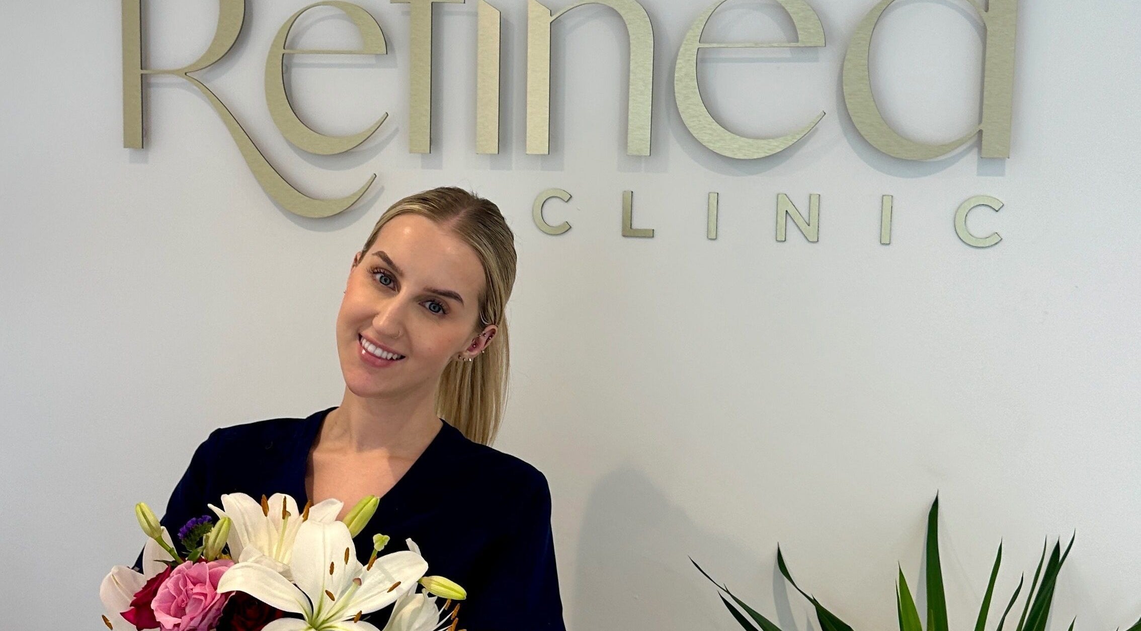 Staff member with flowers at Refined Clinic, Baildon, England, GB, smiling warmly.