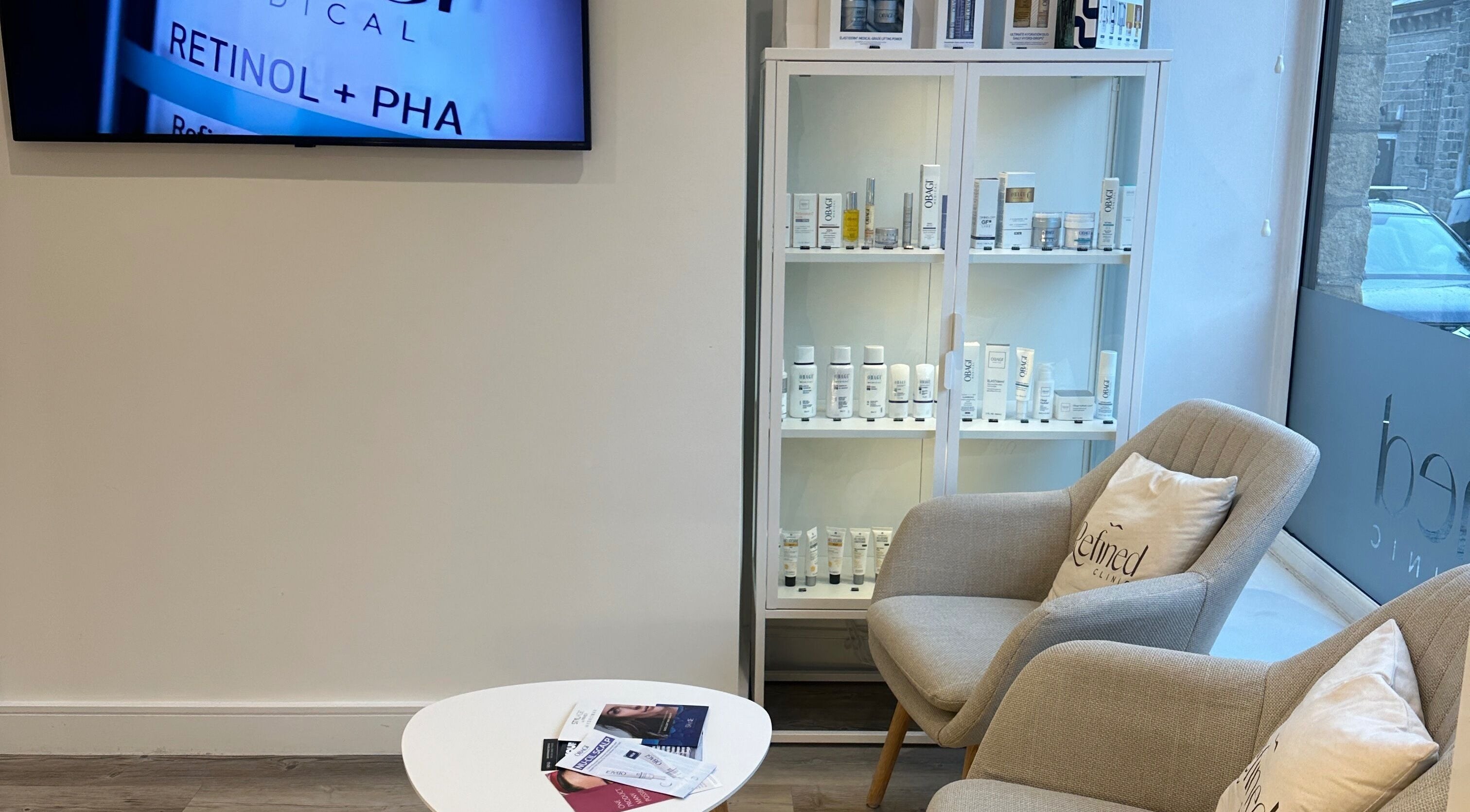 Relaxing seating area at Refined Clinic in Baildon, England, GB showcasing skincare products.