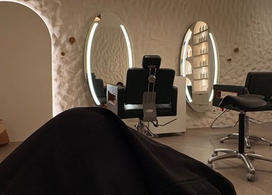 Ambiente elegante em Dunia Zayed, São Paulo, mostrando cadeiras e espelhos iluminados.