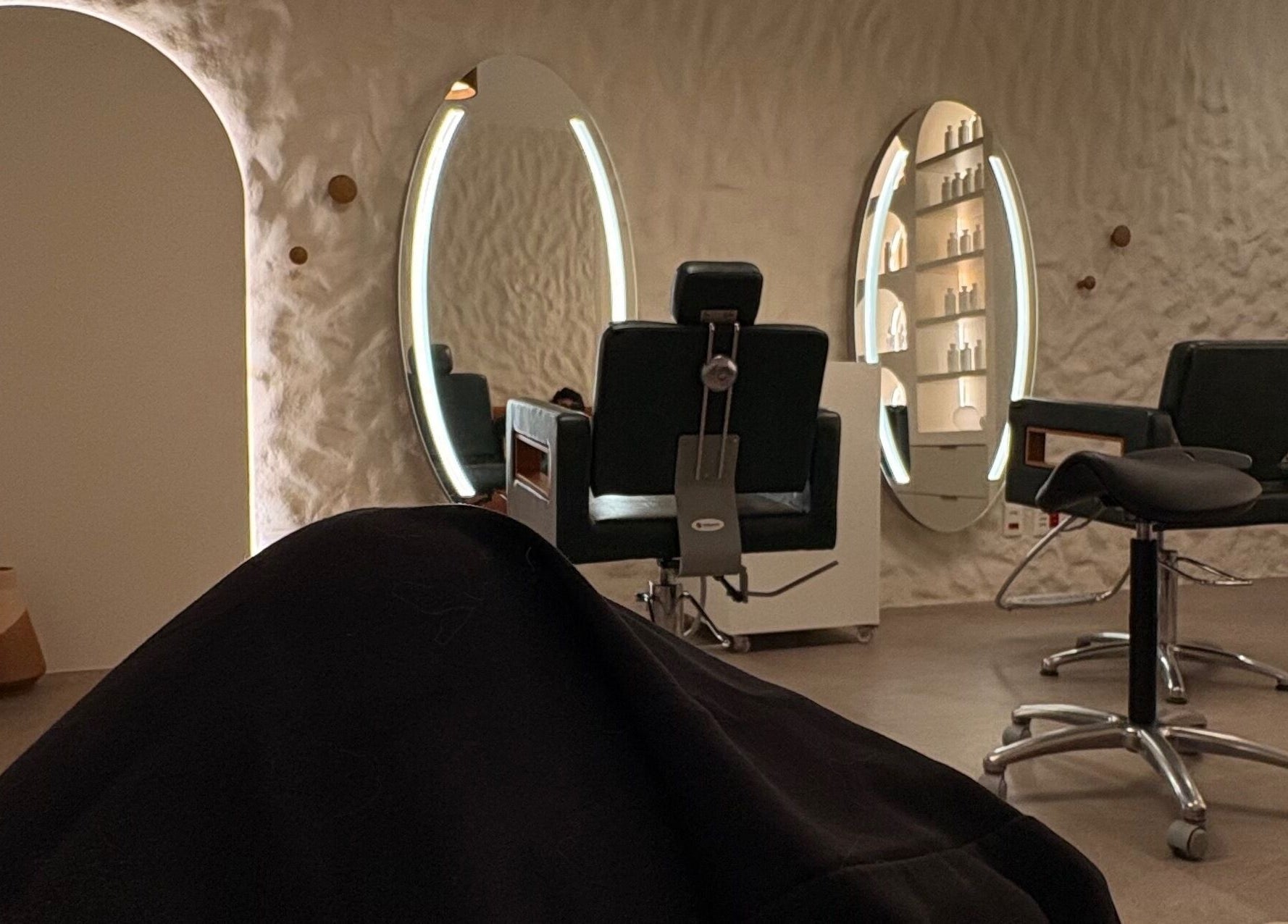 Ambiente elegante em Dunia Zayed, São Paulo, mostrando cadeiras e espelhos iluminados.