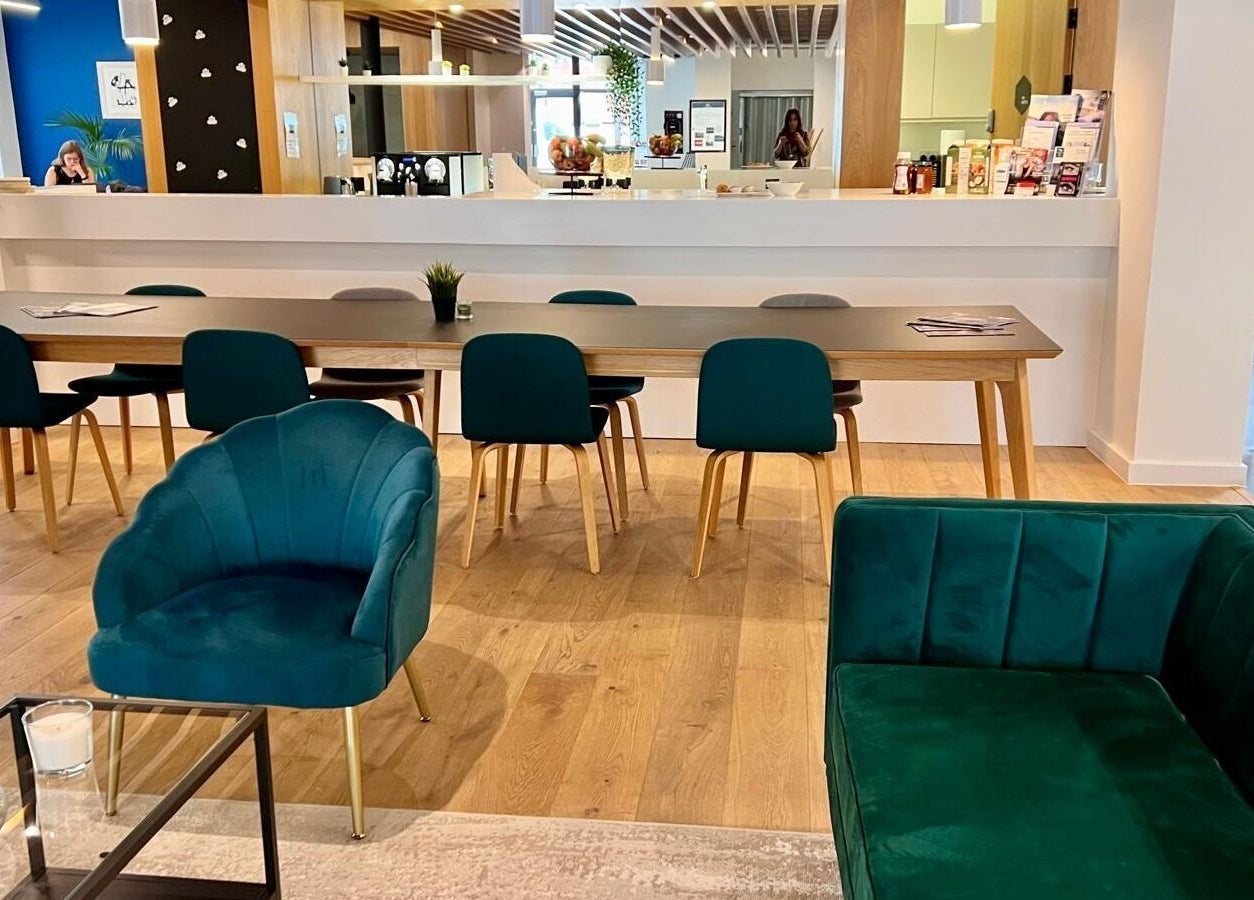 Modern lounge seating area at Lashes London Mobile Service, London, England, GB, featuring teal chairs and wooden decor.