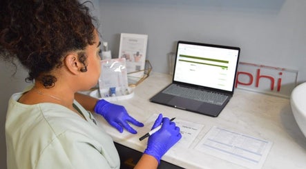 Staff member at Rsg Aesthetics preparing documents at laptop in Cape Town, Western Cape, ZA.