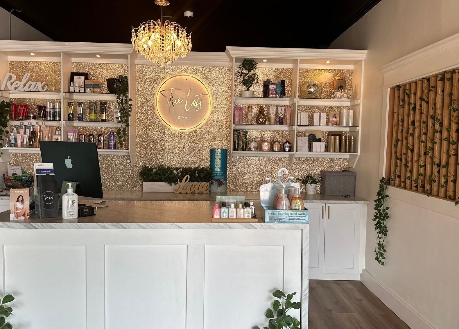 Elegant reception area at The Loft Spa, Barrington Passage, Nova Scotia, CA with chandelier and product display.