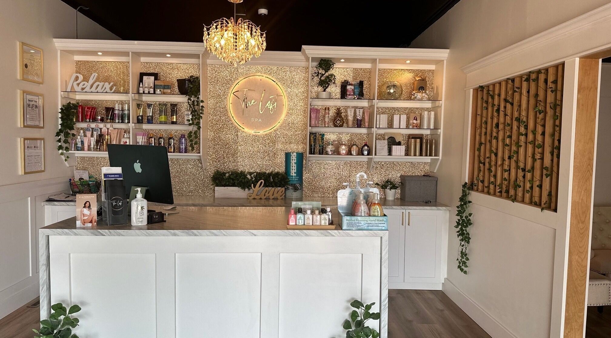 Elegant reception area at The Loft Spa, Barrington Passage, Nova Scotia, CA with chandelier and product display.