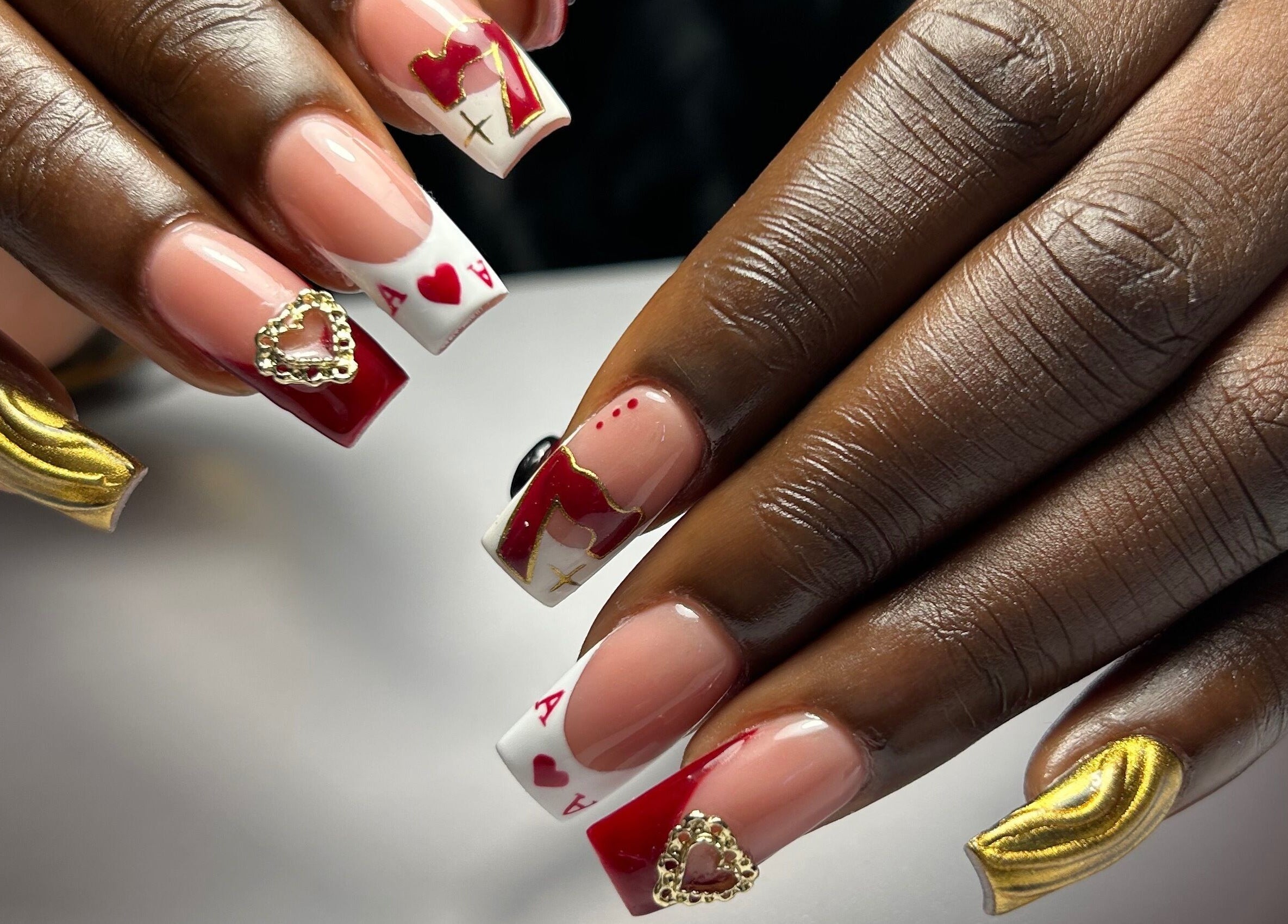 Intricately designed nails at Mimisnailbar, Barkingside, Ilford, England, GB showcasing red, gold, and heart motifs.