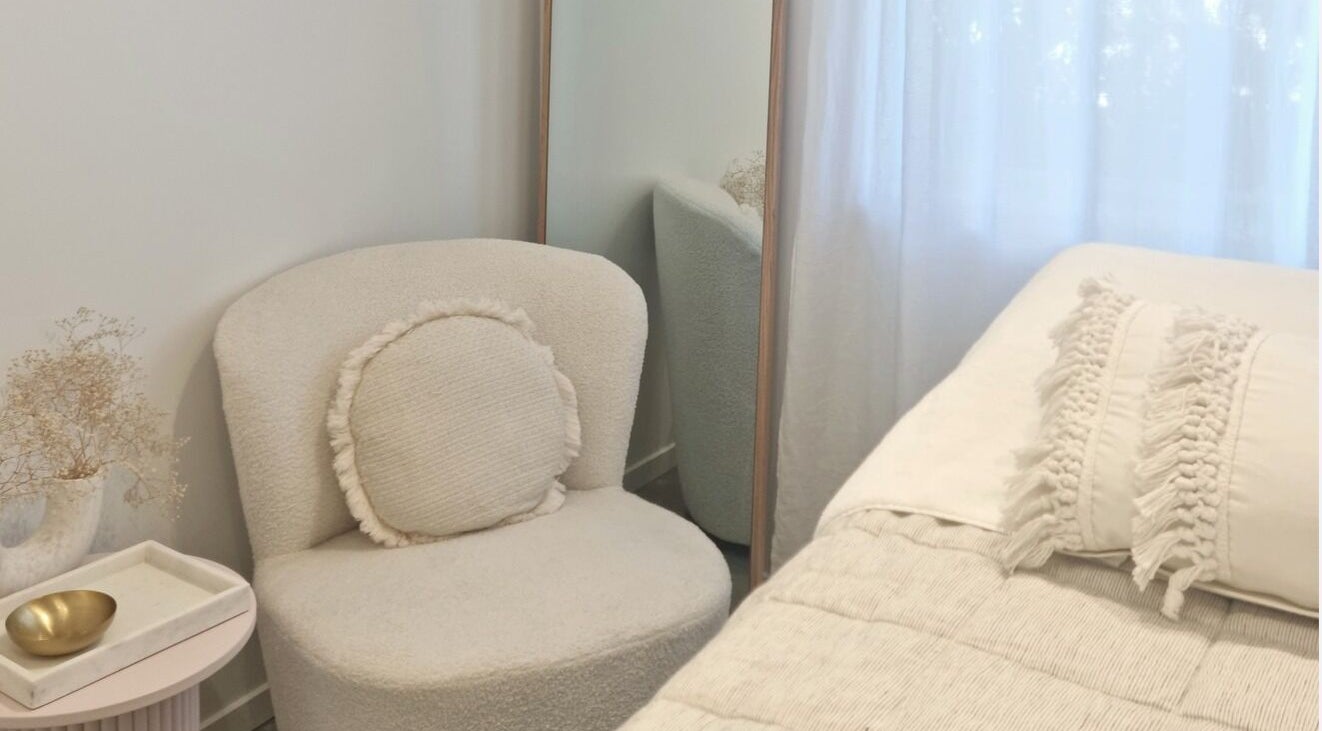 Cozy white seating area in Room of Beauty, Papamoa, Bay Of Plenty, NZ with plush chair and modern decor.