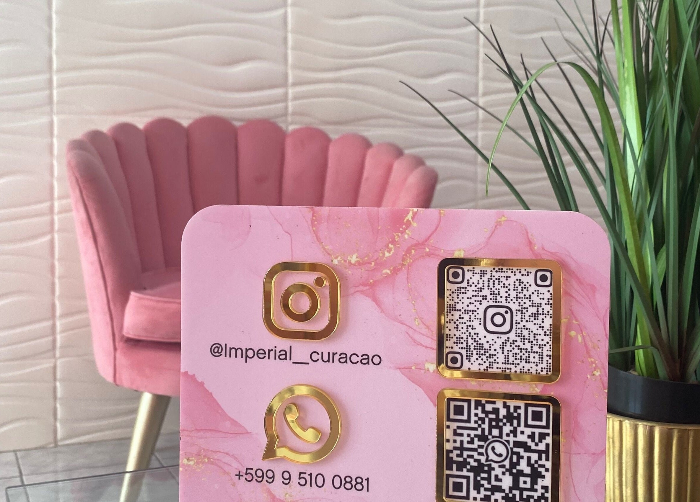 Stylish contact card at Imperial Curacao in Willemstad, Curaçao, CW beside pink velvet chair and green plant.